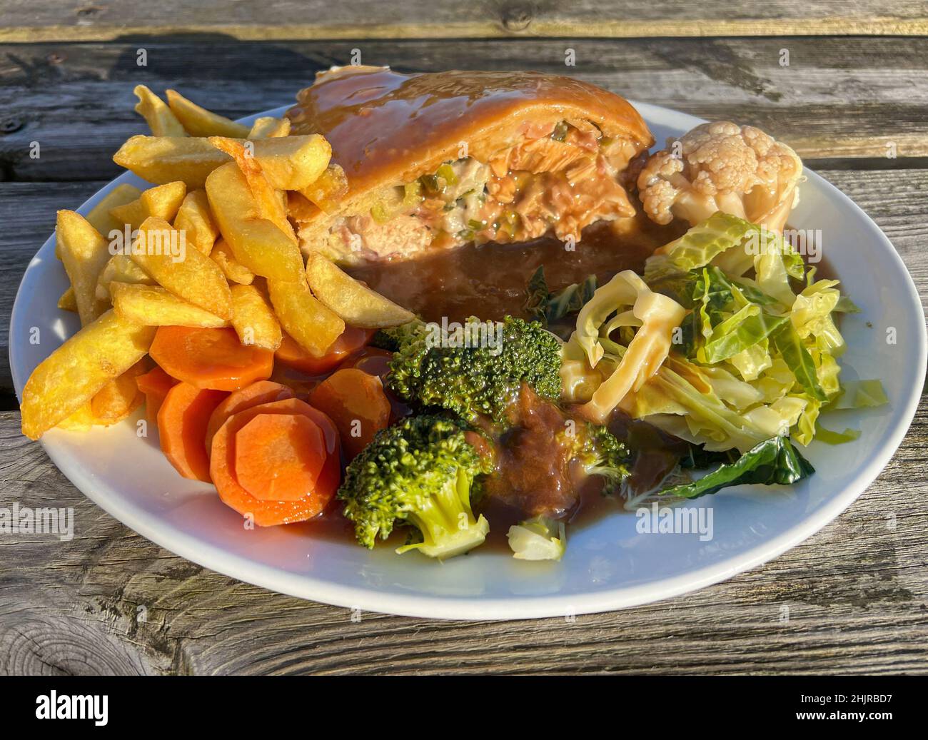 Slice of chicken and ham pie with fries, vegetables and gravy dinner Stock Photo
