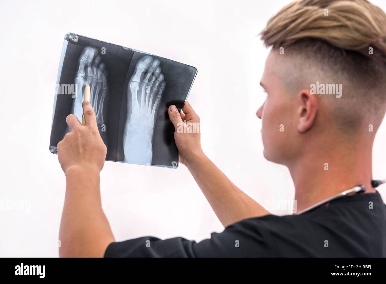 Handsome and young doctor holding foot x-ray of a patient . Medical help concept Stock Photo