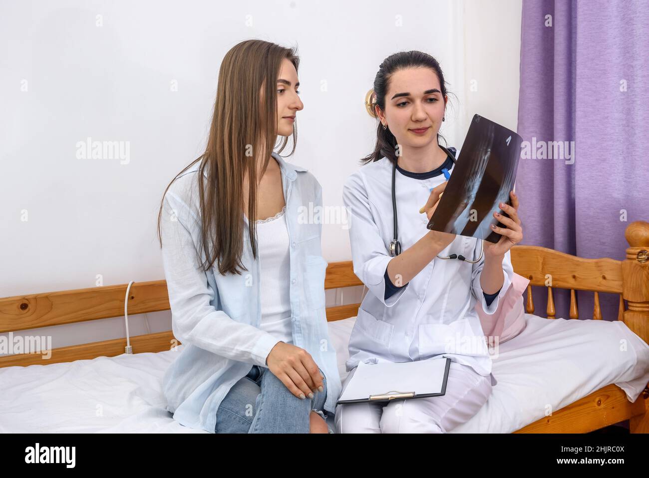 Doctor and patient sitting on sofa in hospital. Doctor explaining to patient her foot x-ray Stock Photo