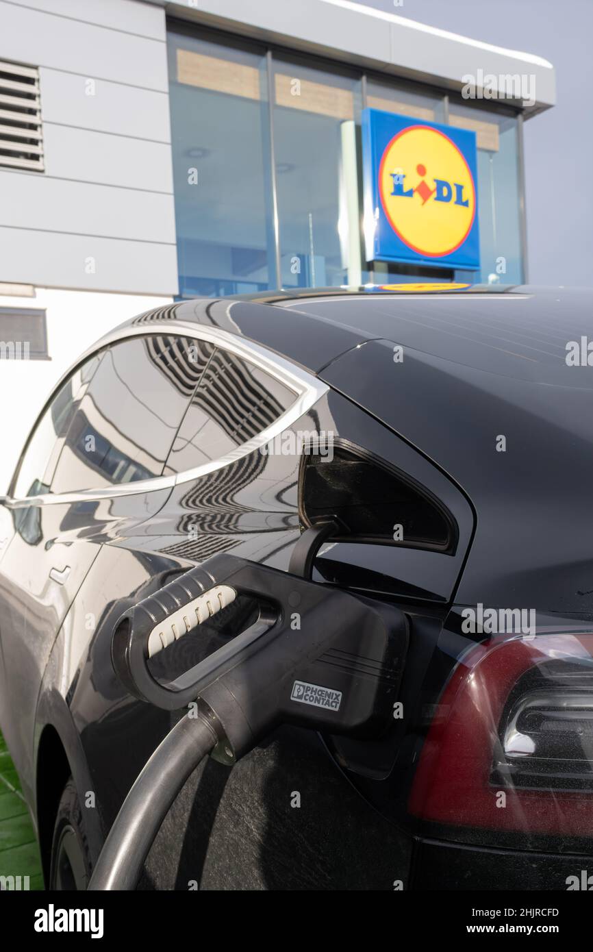 Wernberg, Austria - January 7, 2022. A static shot of a solid black Tesla Model 3 dual motor charging at the LIDL supermarket DC charging station in a Stock Photo