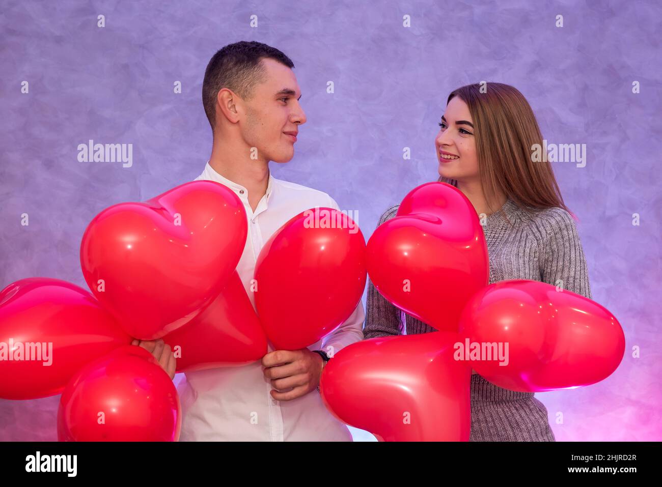 Happy couple in love posing with red air balloons in shape of heart ...