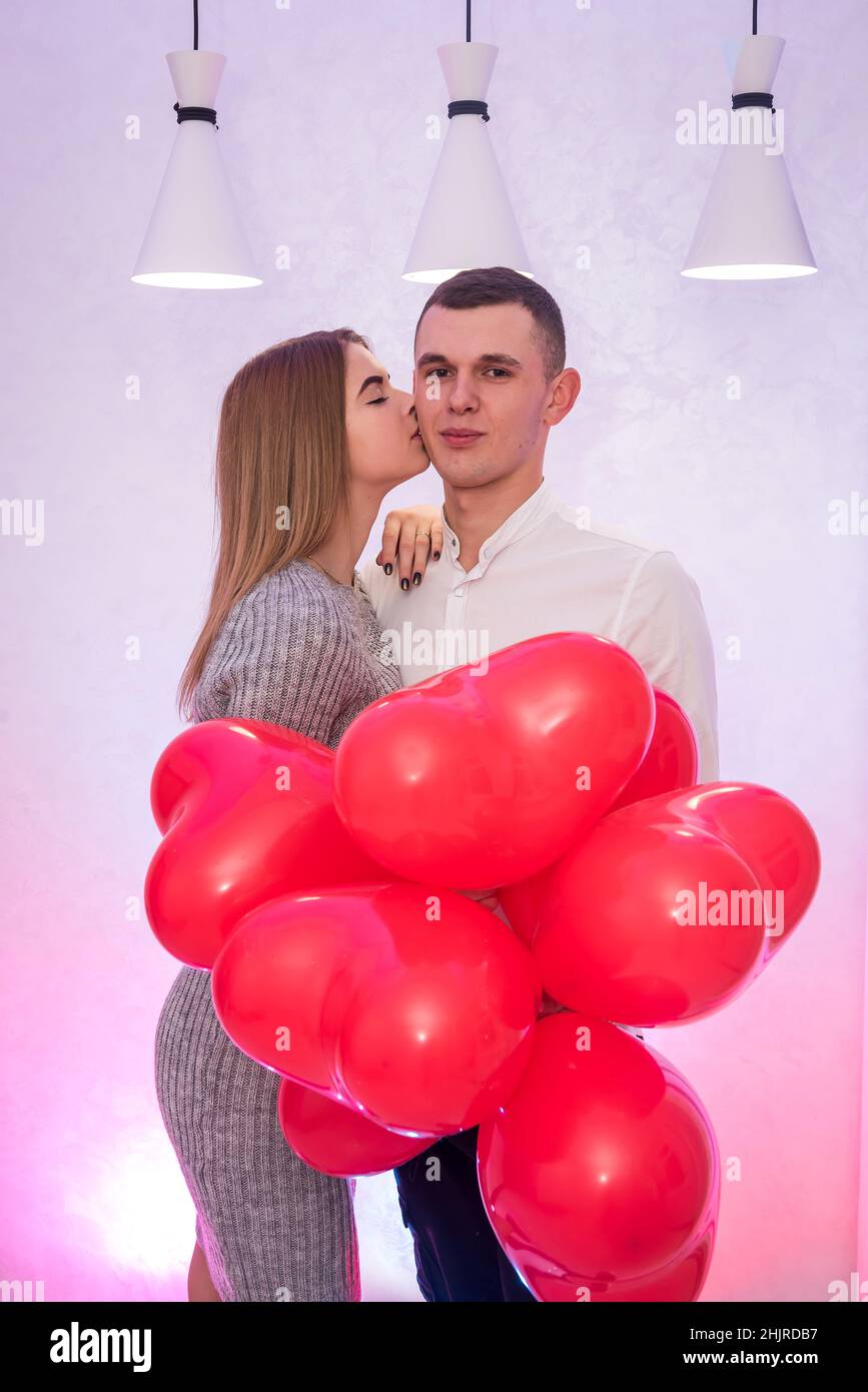 Beautiful woman kissing her man. Celebrating Valentine's day with air balloons Stock Photo