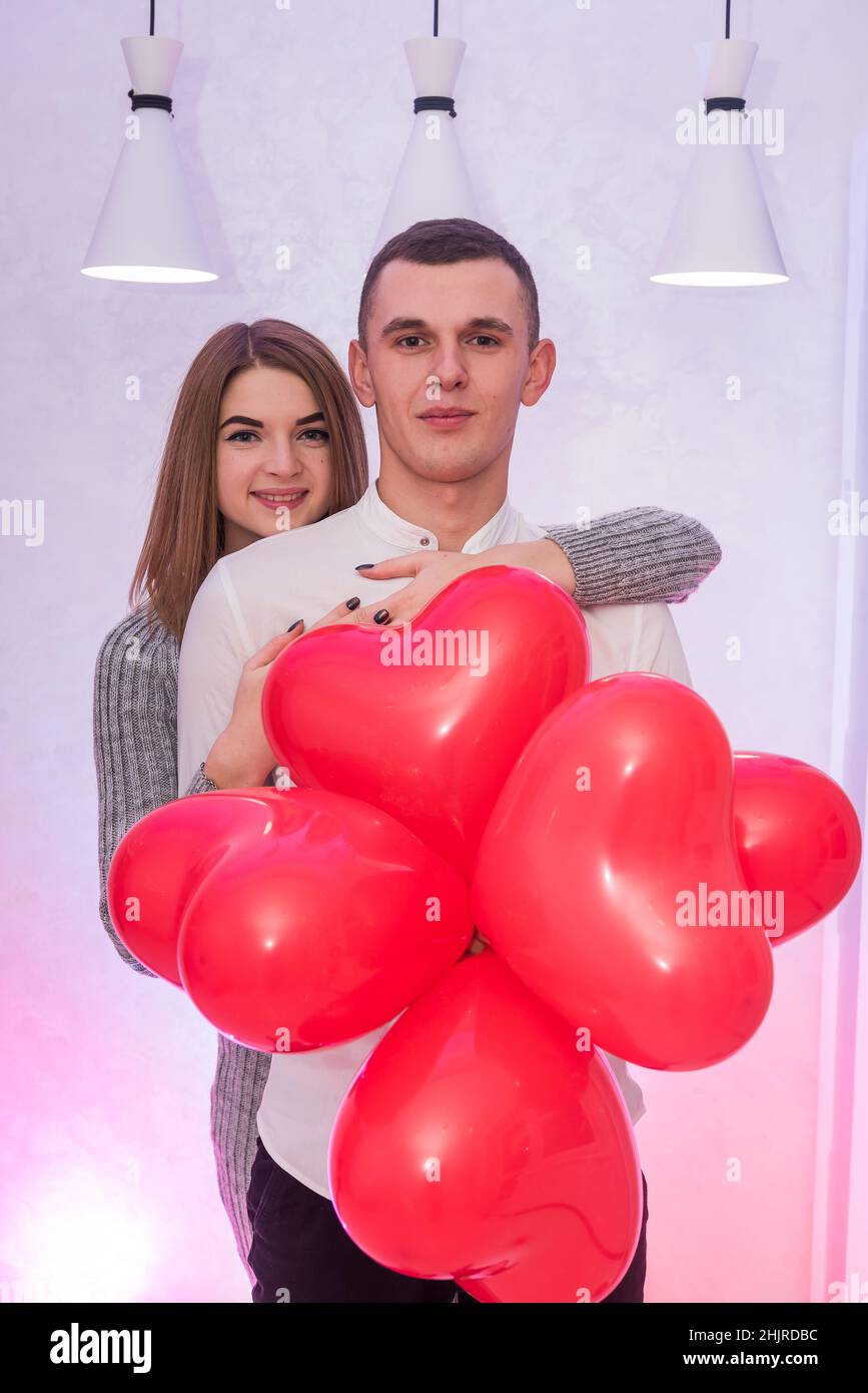 Attractive pair with red air balloons smiling in studio. Couple in love Stock Photo