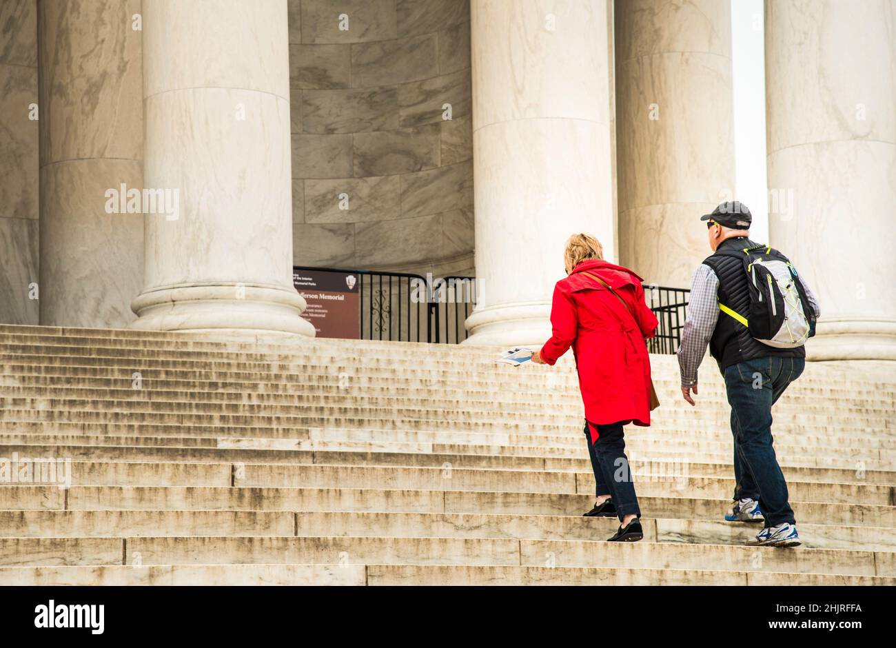 Couple walking up cement steps with columns Stock Photo