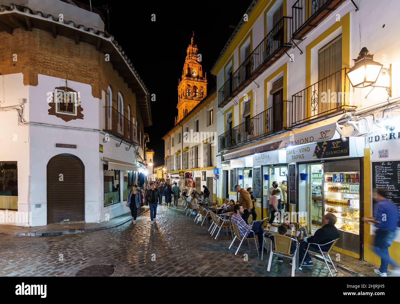 Cordoba, Spain - November 13 2021: People have a drink and food in the Jewish Quarter, the Juderia, in Cordoba old town in Andalusia with the cathedra Stock Photo