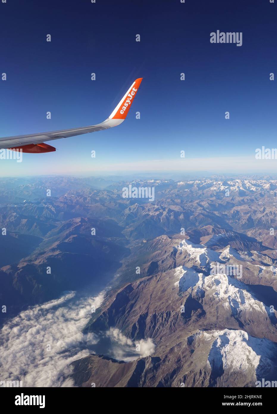 Annecy, France - November 15 2021: View of an Easyjet airplane that flies above the French alps on a sunny day. Stock Photo