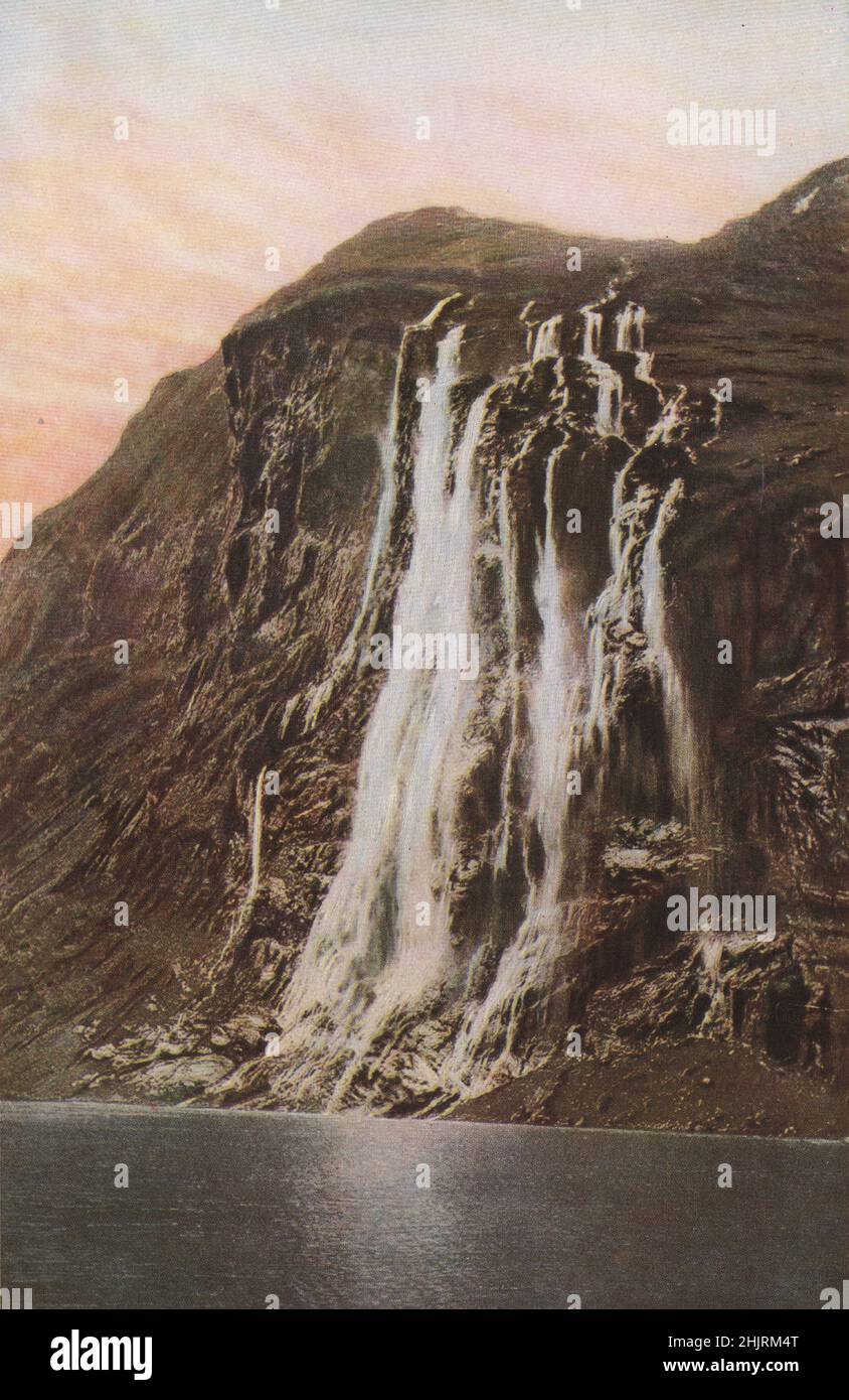 Water and spume veil the great cliffs of the Geirangerfjord, as the Seven Sisters Falls make the downward plunge. Norway  (1923) Stock Photo