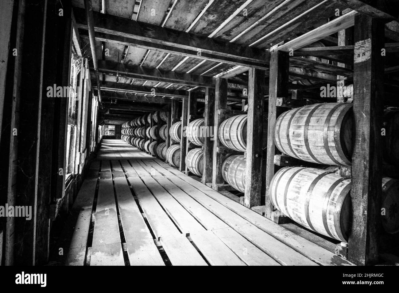 Visiting a bourbon distillery rick house. Looking down the aisle at all the rows of barrels aging. Stock Photo