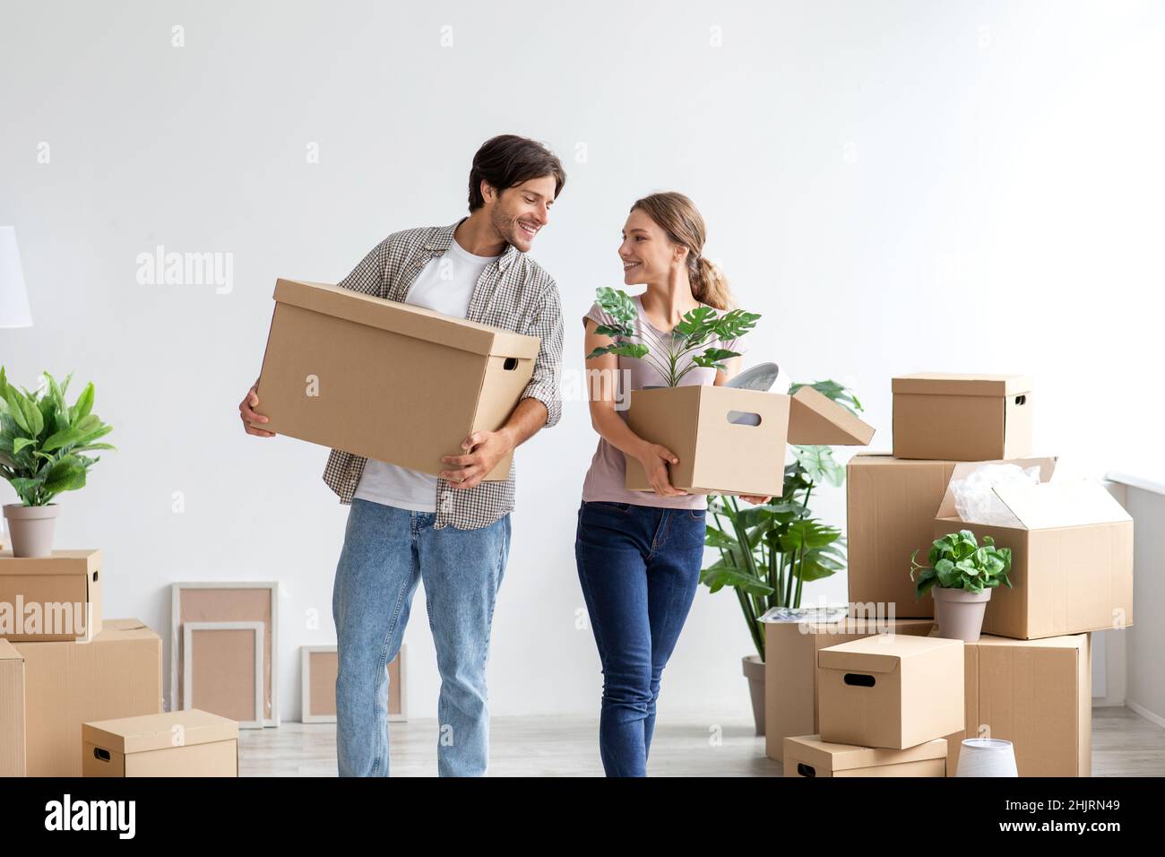 Laughing young caucasian couple carry cardboard boxes with stuff and ...