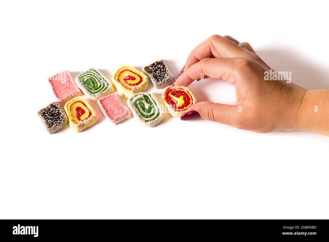 Female hand picking piece of turkish delight, isolated on a white with copy space. Stock Photo