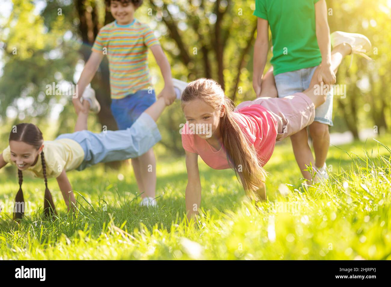 Boys holding legs of girls leaning hands on grass Stock Photo Alamy