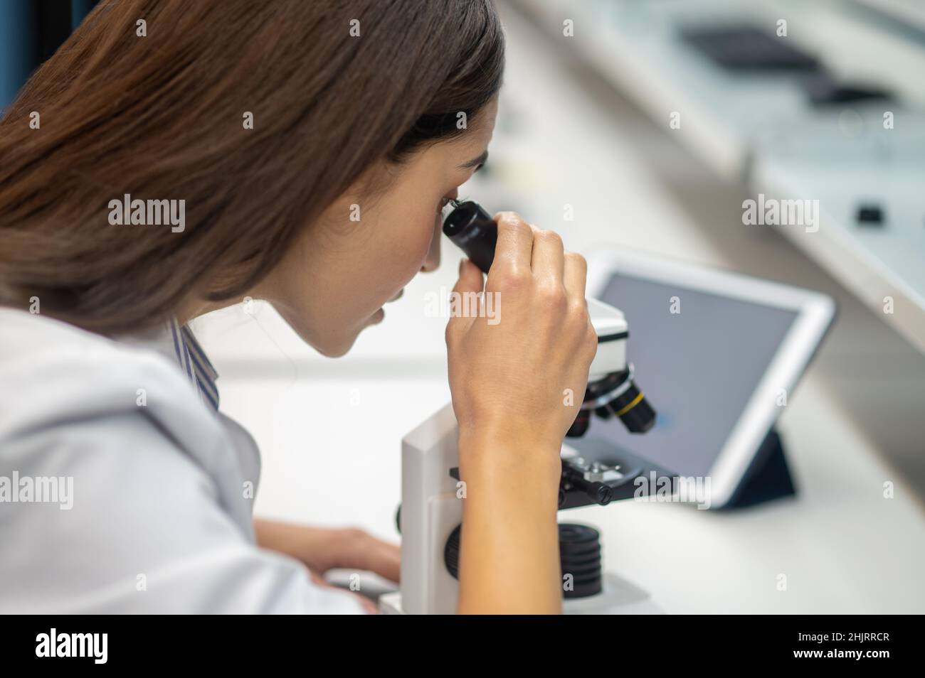 Closeup of womans face looking through microscope Stock Photo Alamy