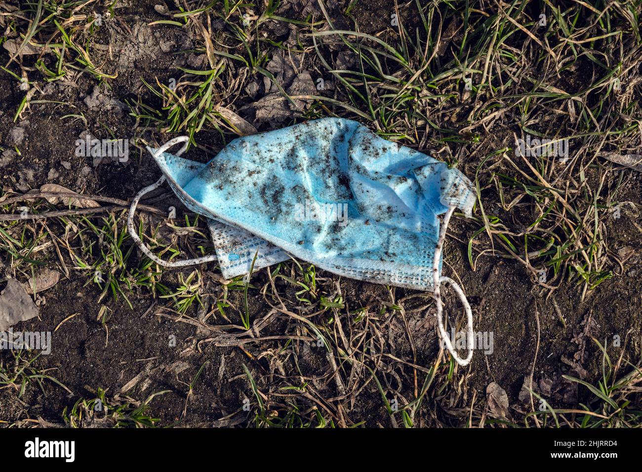 Old face mask thrown on a ground Stock Photo