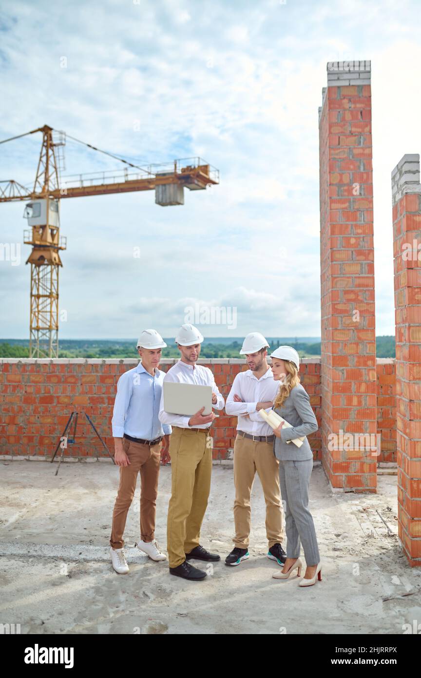 Concentrated young construction engineer surrounded by his colleagues outdoors Stock Photo