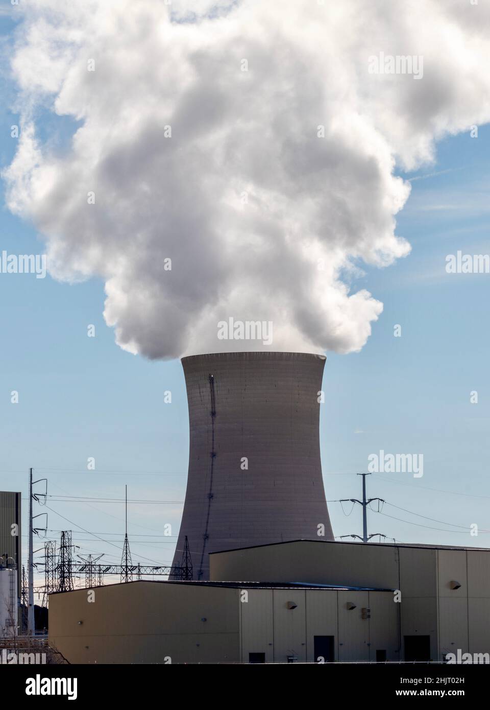 power plant smoke stack with smoke against blue sky Stock Photo