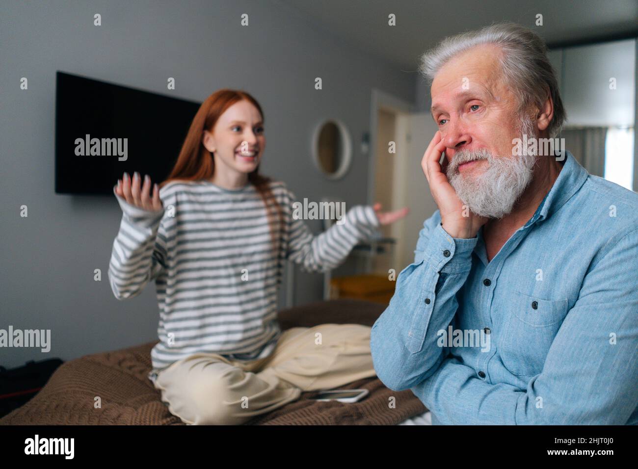 Cheerful young woman and mature male having fun, enjoying leisure time, sharing news at home. Stock Photo