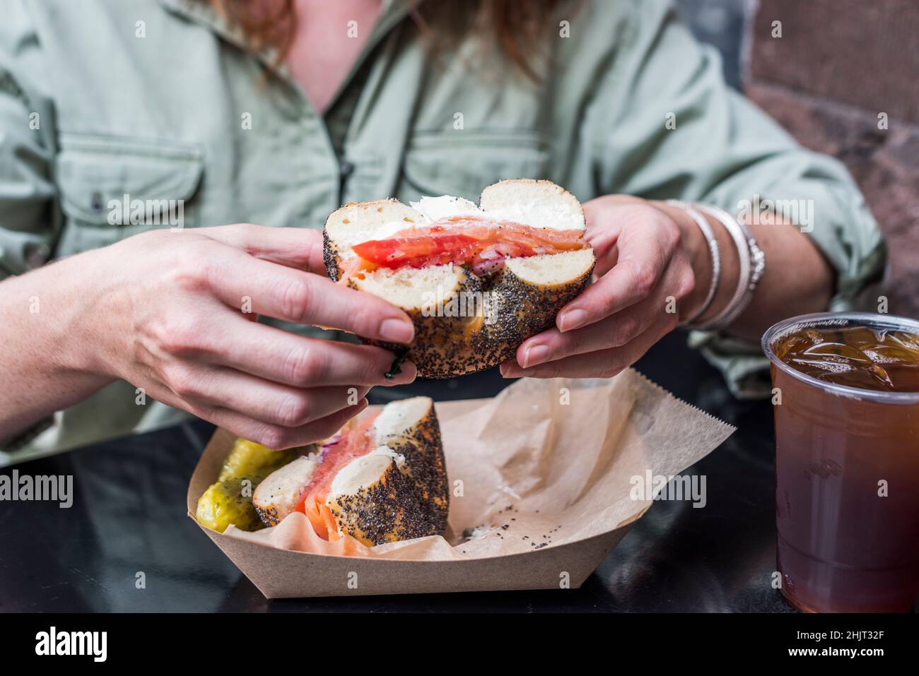 Women holding a poppyseed bagel with smoked fish, tomato and cream cheese. Stock Photo