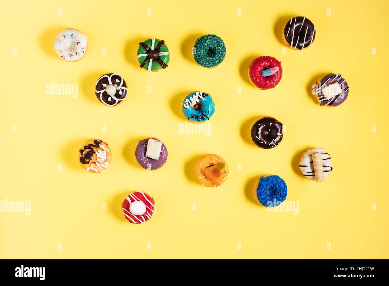 Colorful donuts or doughnuts in various shapes on yellow bright background. Colorful and happy image and concept. Stock Photo