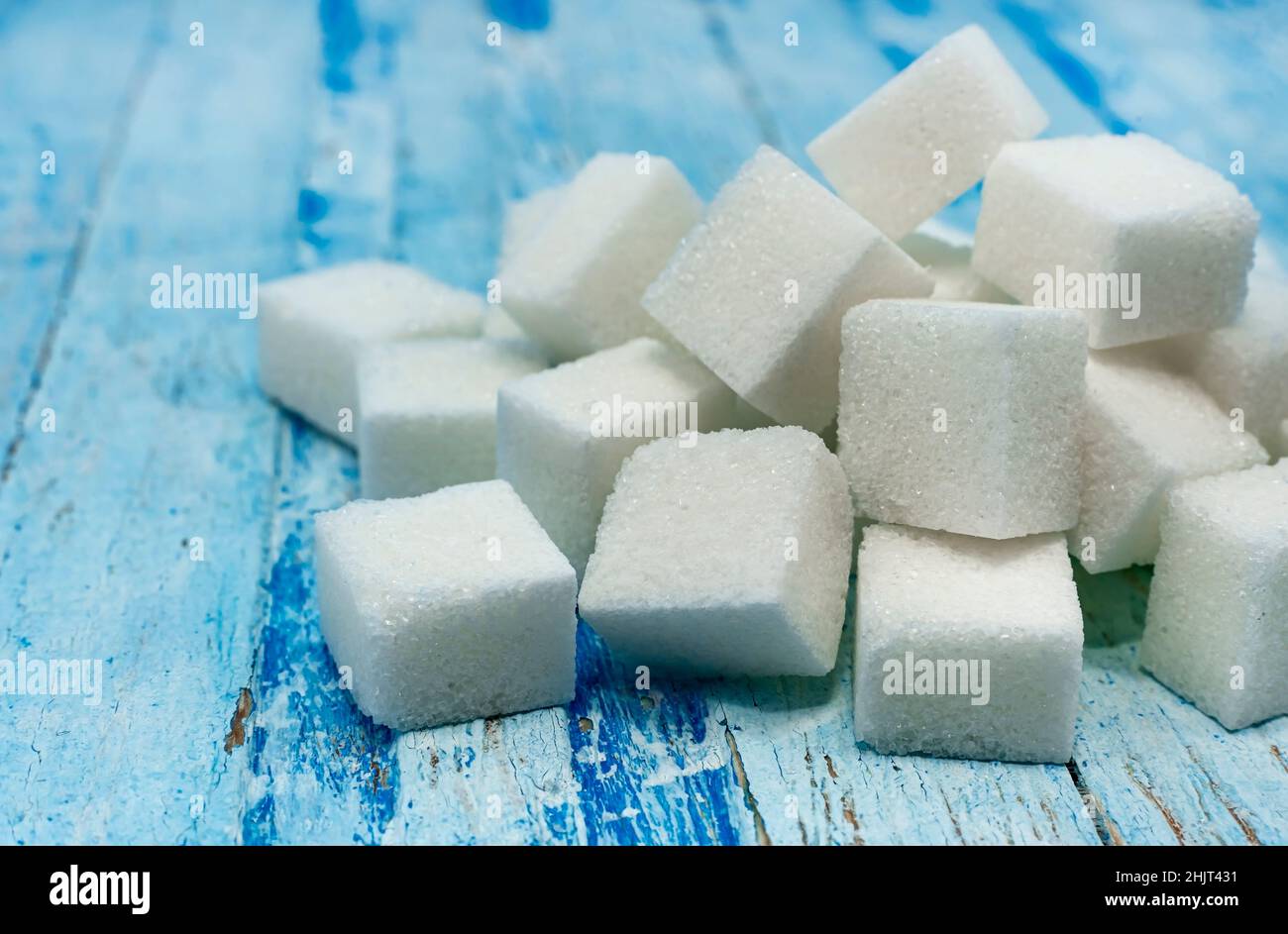 Sugar cubes. Refined sugar scattered on a wooden surface close-up Stock Photo