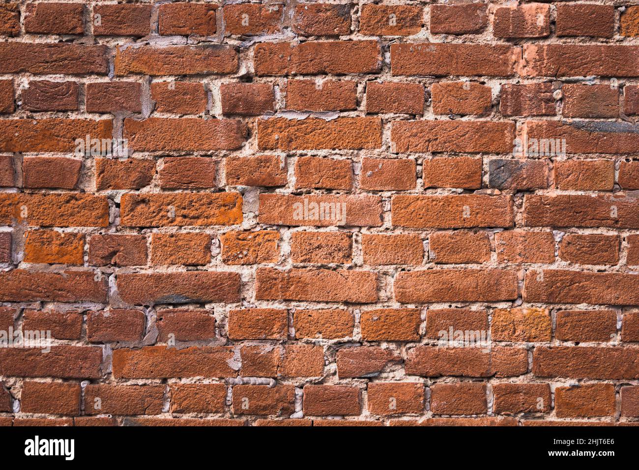 Wall of old red clay bricks. Ruined vintage stone background. Rough
