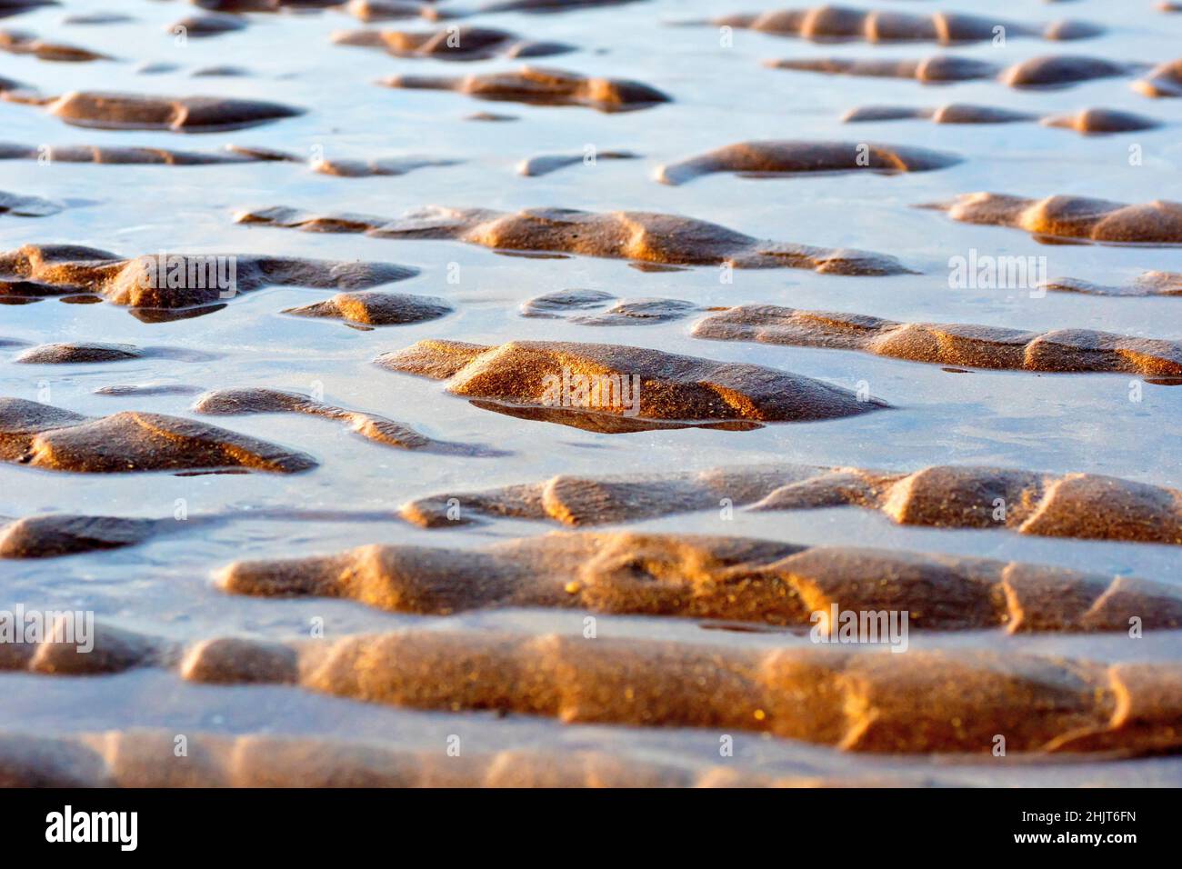 A low level shot of the ripples created in the sands of a beach with ...