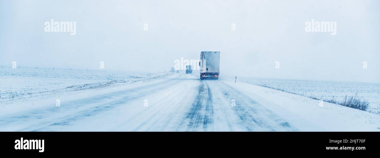Freight transportation truck on the road in snow storm blizzard, bad weather conditions for transportation event, selective focus Stock Photo