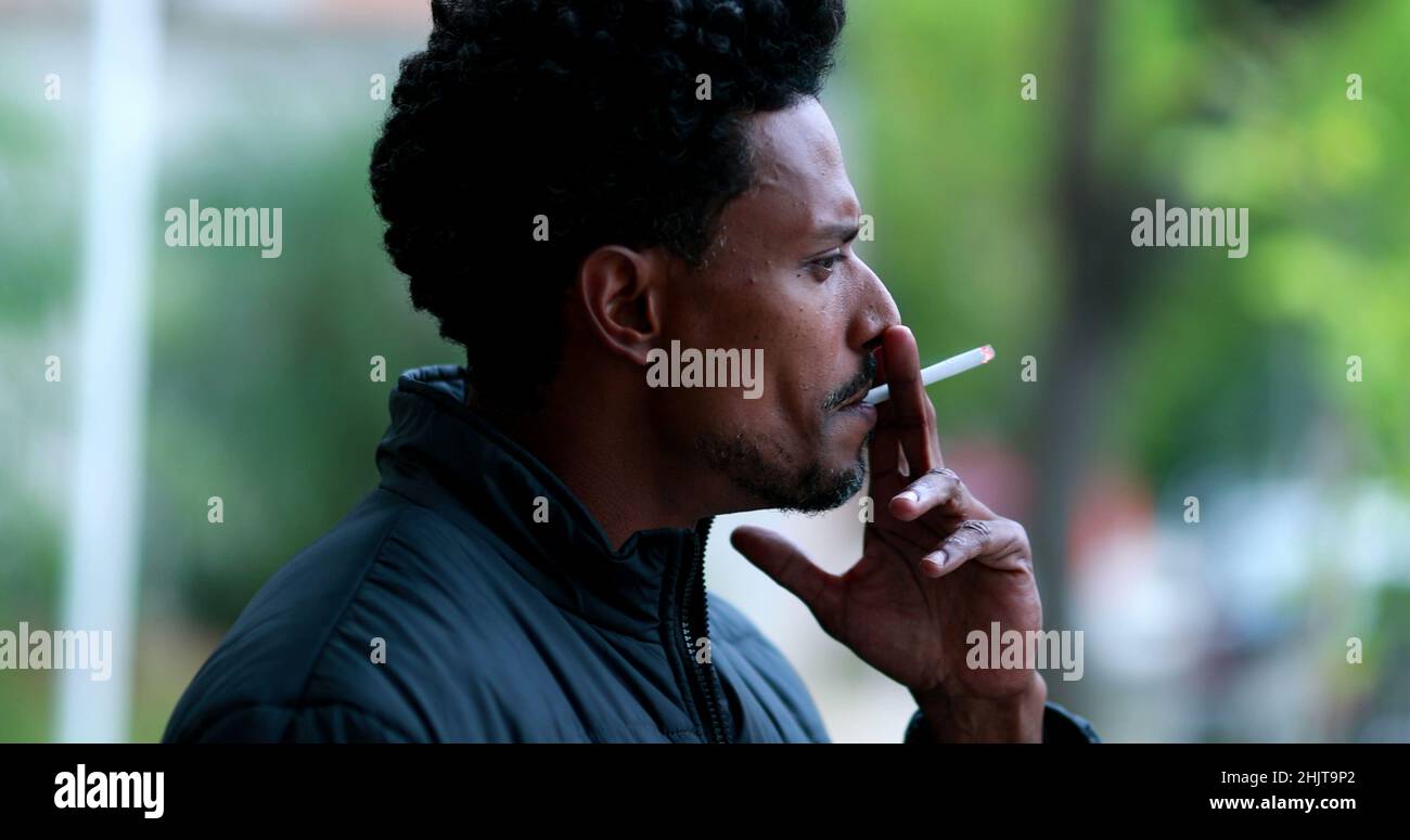 Pensive black african man smoking cigarette outdoors Stock Photo