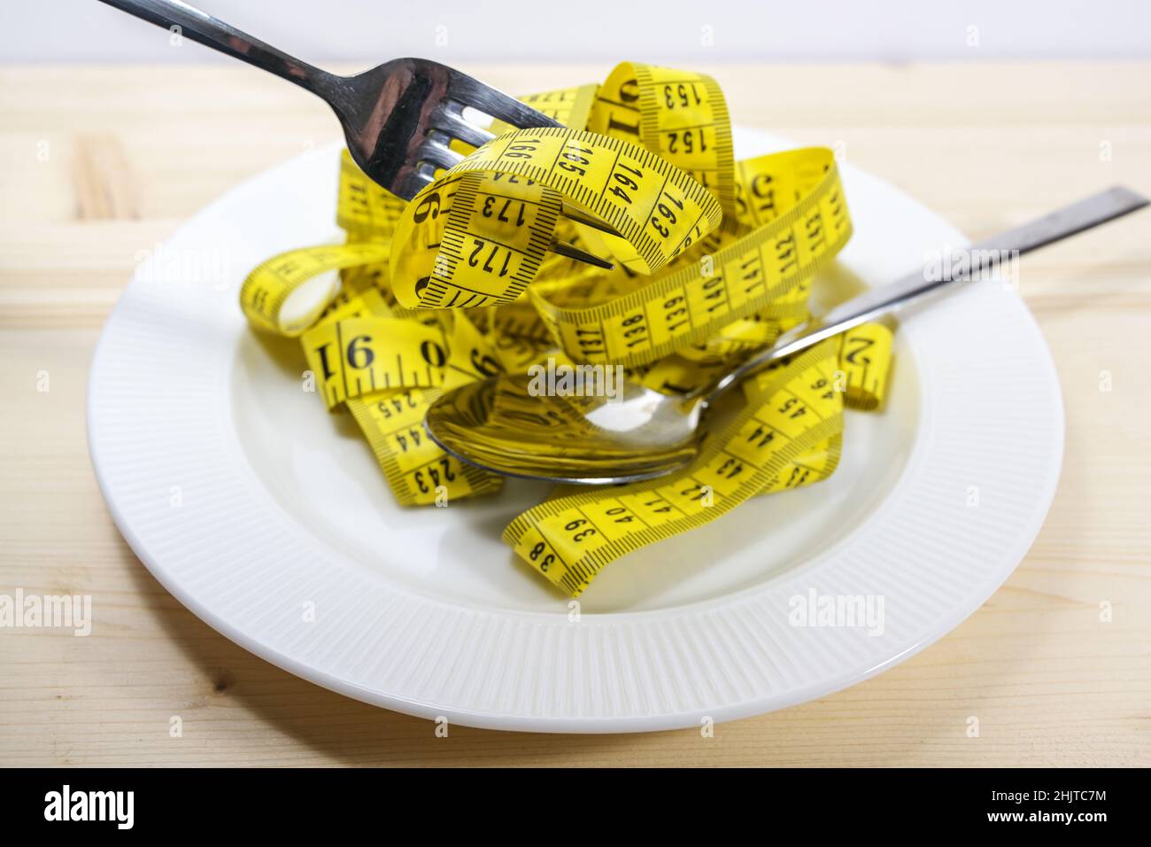 Tape measure like pasta on a plate with fork and spoon, diet concept to