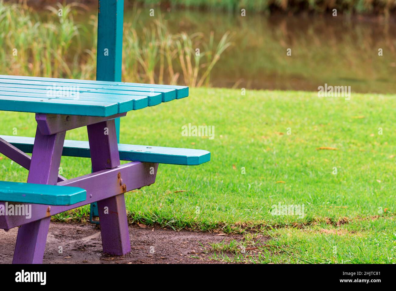 A park bench picnic table and seat near lush green grass and a small