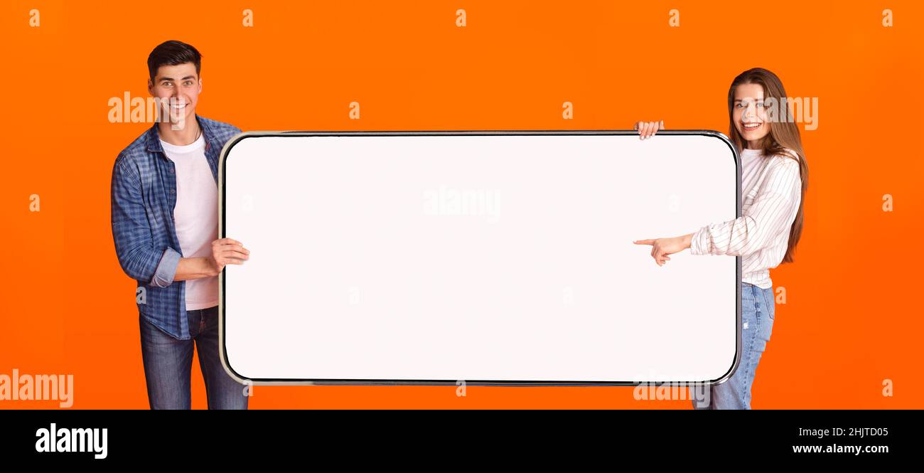 Excited couple pointing at white empty smartphone screen Stock Photo