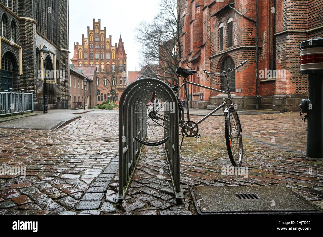 Cycle in the rain locked on the public bicycle stand in the churchyard of St. Mary's Church, Lubeck, Germany, copy space, selected focus, narrow depth Stock Photo