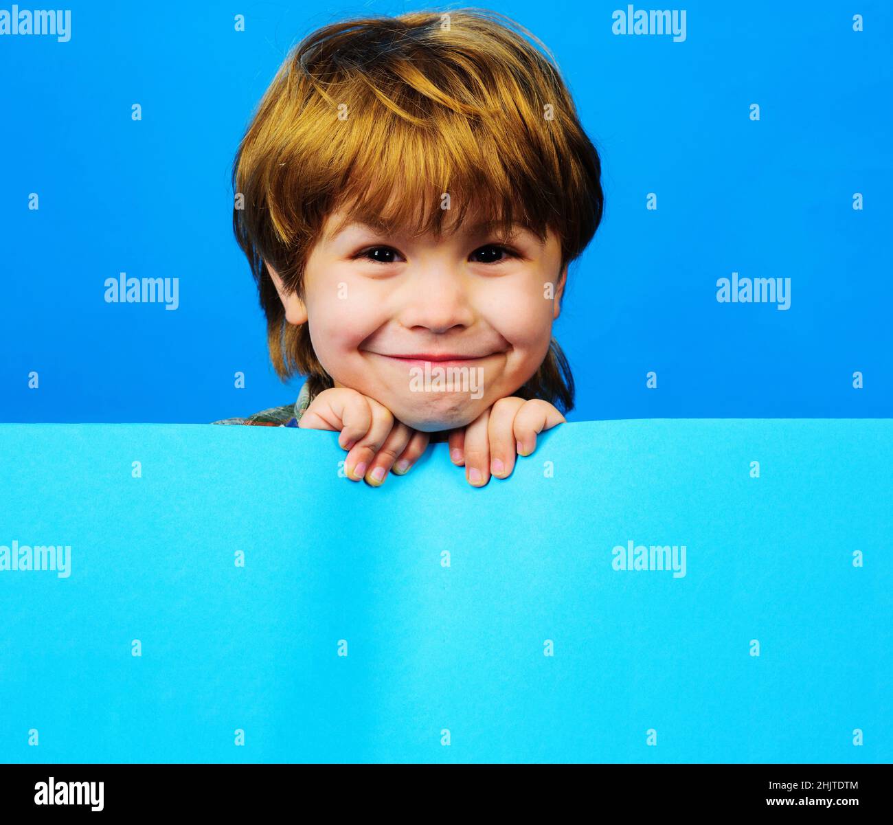 Smiling Child with advertising board. Shopping. Sale, Discount. Funny Little Kid with blank placard. Stock Photo