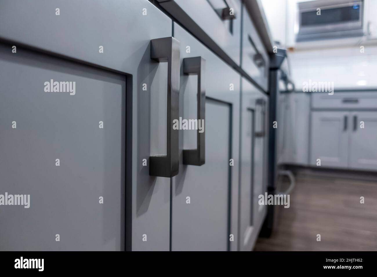 Low angle view of gray kitchen door handles inside a large