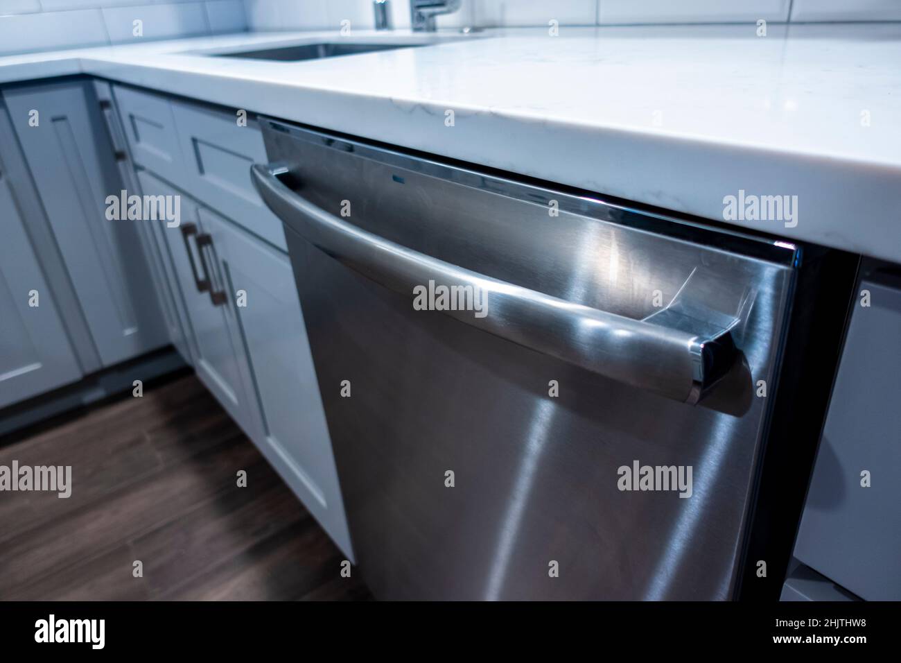 Angled view of a stainless steel dishwasher inside a white and gray