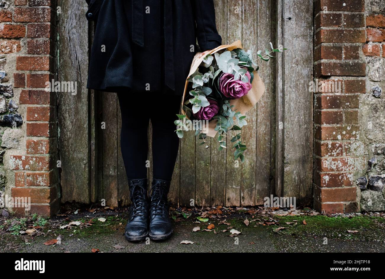 womens boots by an old English door with a bouquet of flowers Stock Photo