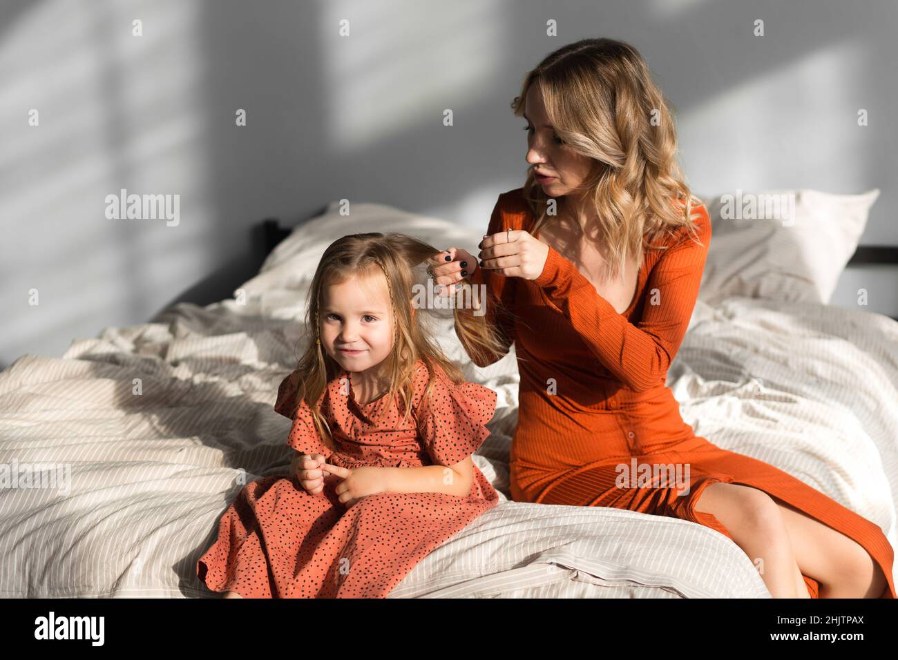 Mother combing her daughter's hair in bed Stock Photo