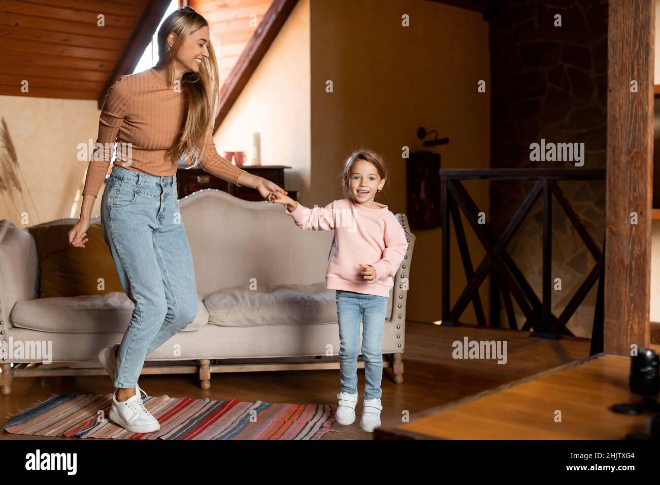 Positive mother dancing to music with little girl Stock Photo - Alamy