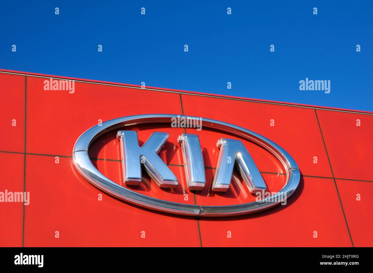 KIA motors brand company logo sign at a car dealership against blue sky. Stock Photo