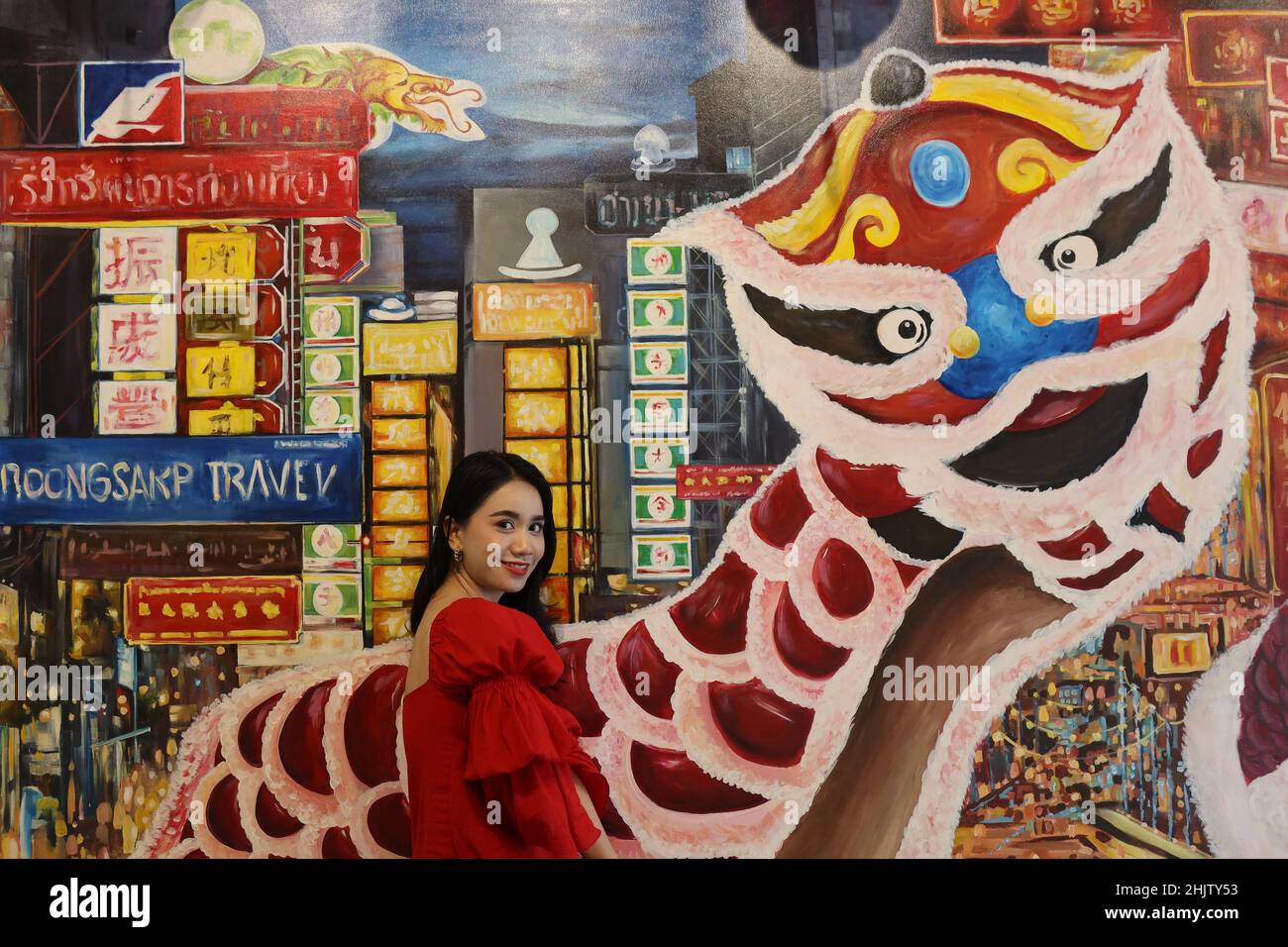 Thai woman smiling in front of a mural of Chinatown, Chinatown, Bangkok, Thailand Stock Photo