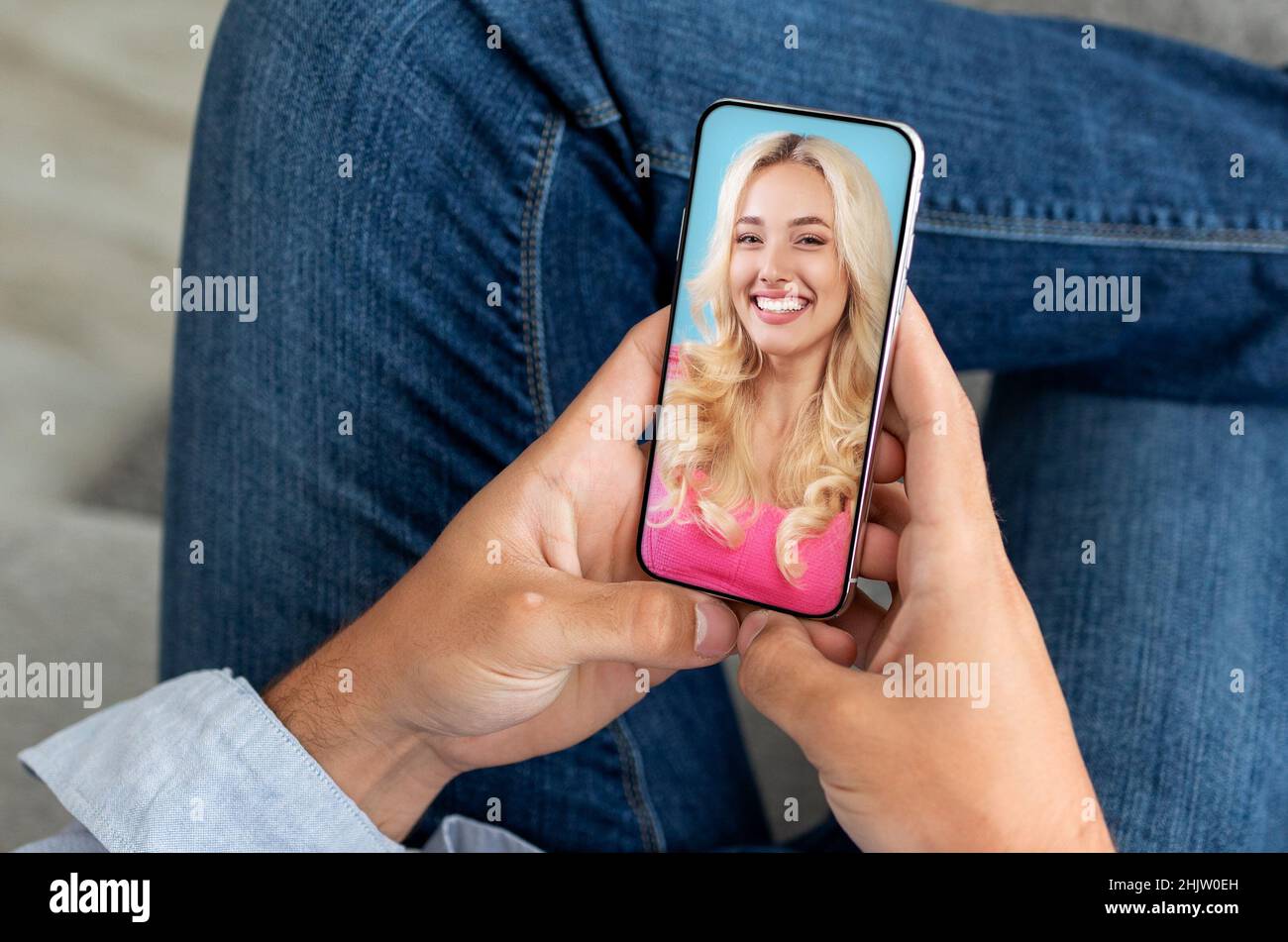 Unrecognizable man using smartphone and having video call with attractive lady girlfriend, sitting at home Stock Photo
