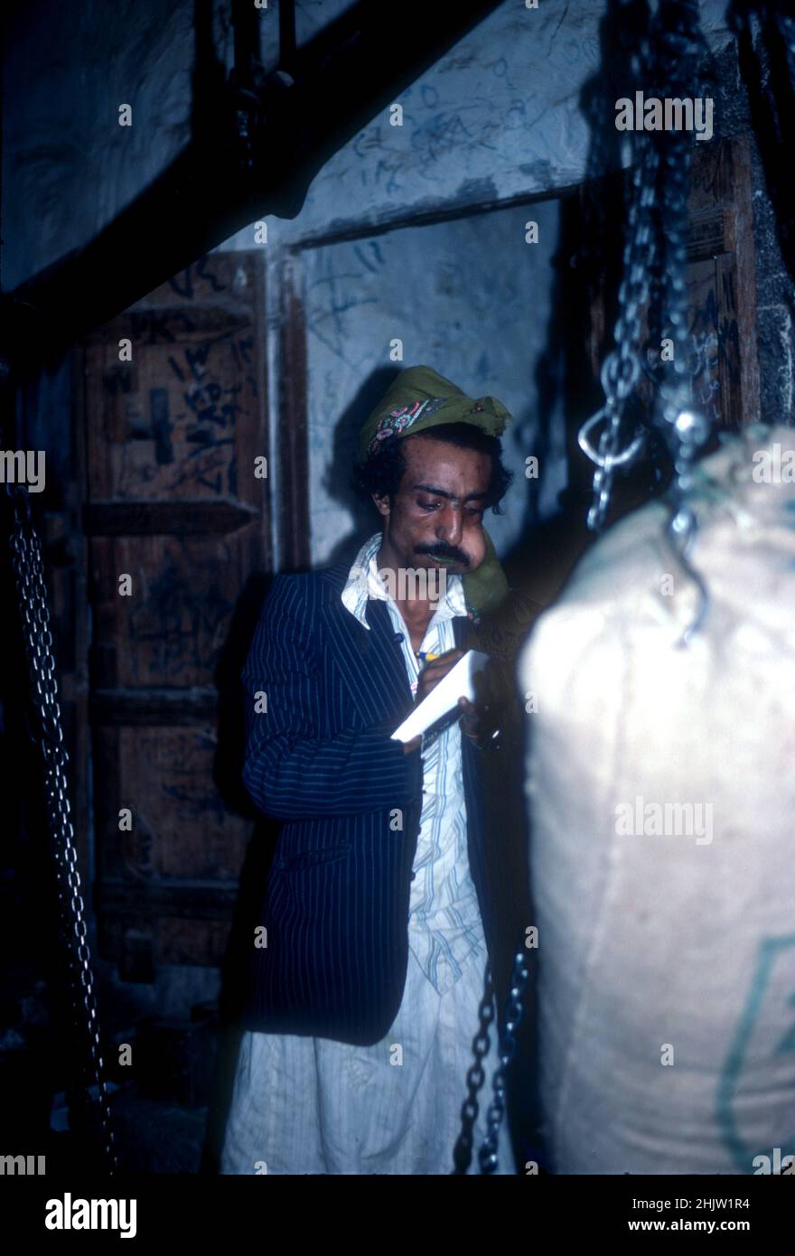 Man weighing sacks of coffee beans. He is chewing qat, Sana'a Yemen Stock Photo