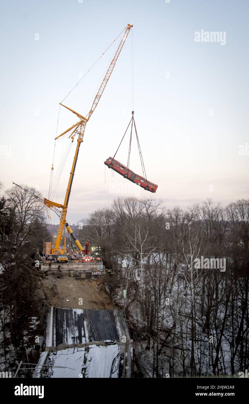 Pittsburgh, United States. 31st Jan, 2022. A crane slowly raises the 60 foot long articulated Port Authority bus from the site of the Fern Hollow Bridge collapse on Monday, January 31, 2022 in Frick Park in Pittsburgh. The bridge collapsed on Friday morning with injuries, but no lost of life. Photo by Archie Carpenter/UPI Credit: UPI/Alamy Live News Stock Photo