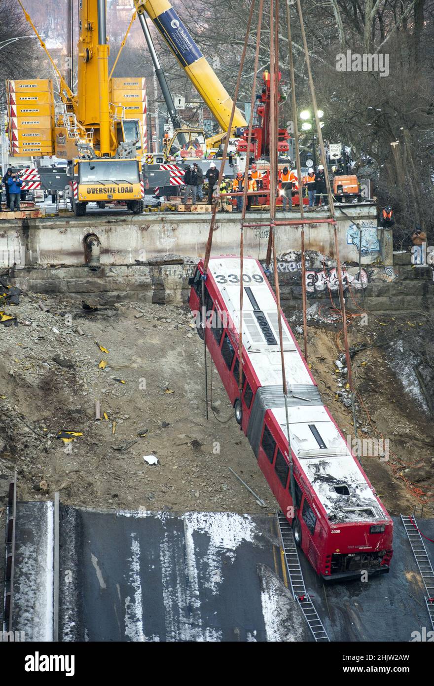 Pittsburgh, United States. 31st Jan, 2022. A crane slowly lifts the 60 foot long articulated Port Authority bus from the site of the Fern Hollow Bridge collapse on Monday, January 31, 2022 in Frick Park in Pittsburgh. The bridge collapsed on Friday morning with injuries, but no lost of life. Photo by Archie Carpenter/UPI Credit: UPI/Alamy Live News Stock Photo