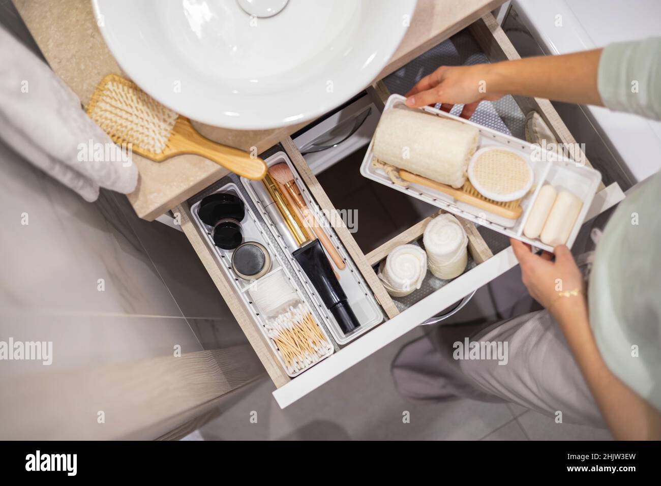 Top view of woman hands neatly organizing bathroom amenities and