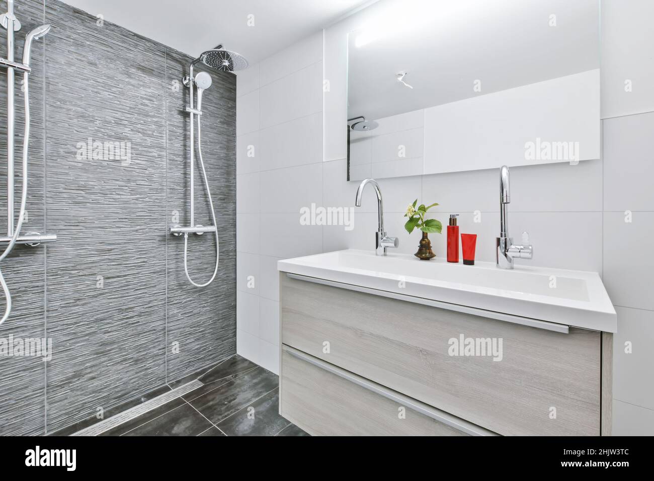 Stylish bathroom with a large mirror and dark tiled floor Stock Photo ...