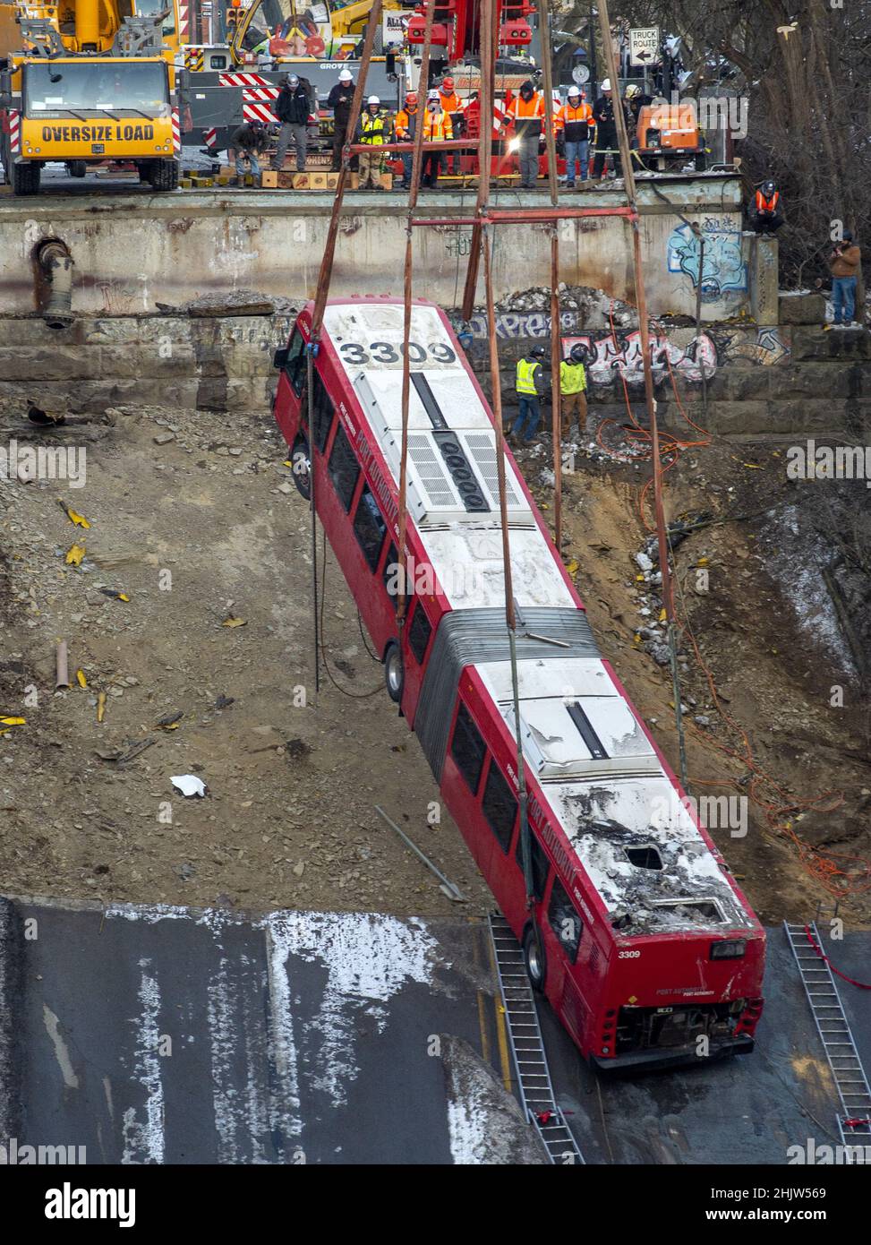 Pittsburgh, United States. 31st Jan, 2022. A crane slowly lifts a 60 foot long articulated Port Authority bus from the site of the Fern Hollow Bridge collapse on Monday, January 31, 2022 in Frick Park in Pittsburgh. The bridge collapsed on Friday morning with injuries, but no loss of life. Photo by Archie Carpenter/UPI Credit: UPI/Alamy Live News Stock Photo