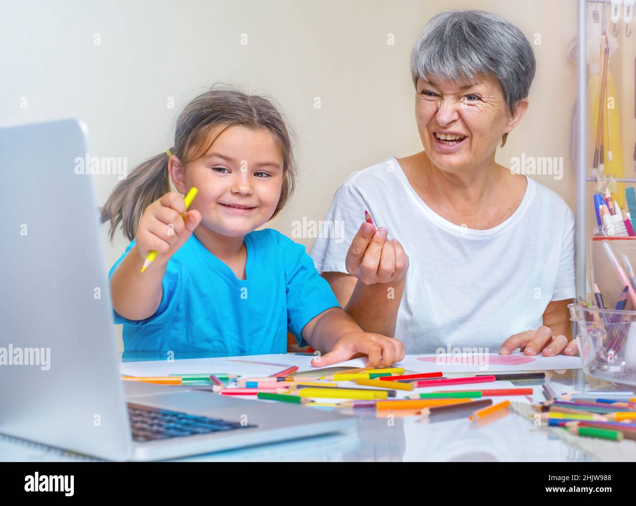Grandmother and child learn to draw together online Stock Photo