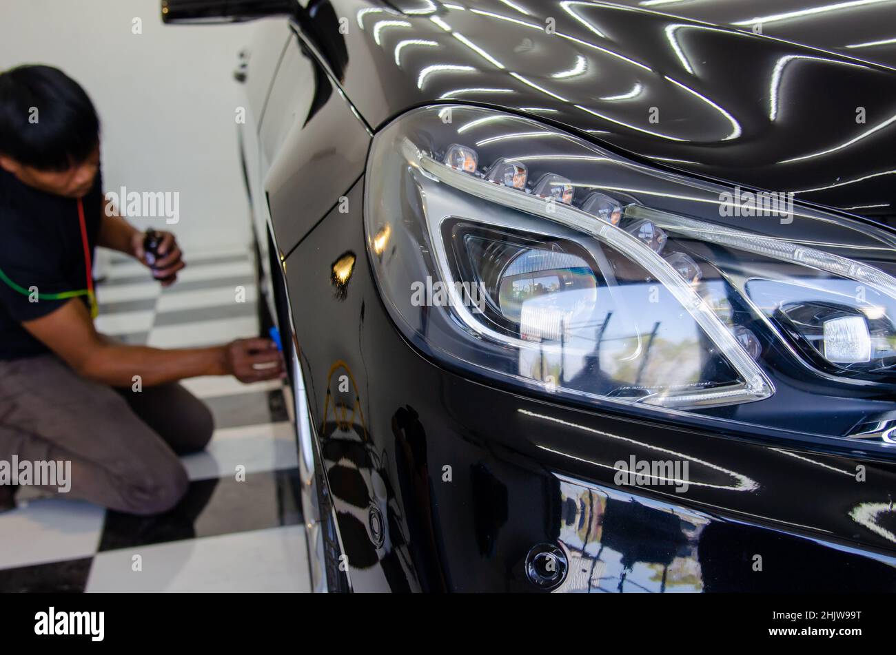 mechanic is coating ceramic glass to prevent scratches on cars.Focus headlights Stock Photo