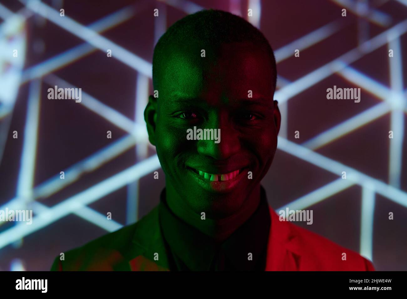 Happy young African man with toothy smile looking at camera while standing against creative background Stock Photo