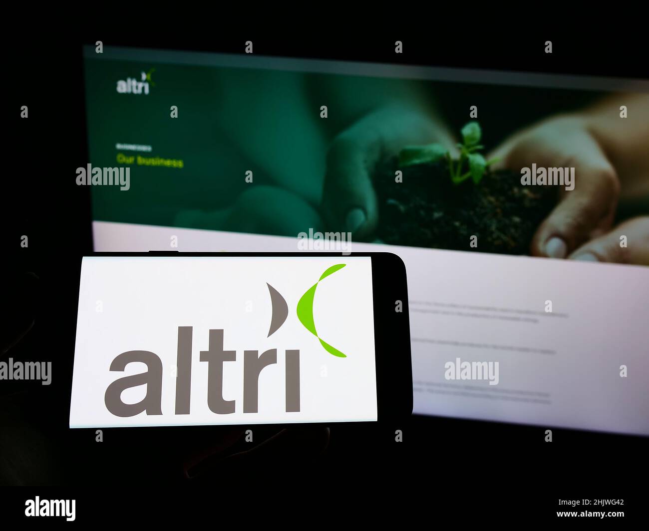 Person holding mobile phone with logo of Portuguese conglomerate Altri SGPS S.A. on screen in front of business web page. Focus on phone display. Stock Photo